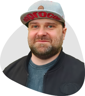 A portrait of me wearing a gray cap and a black bomber jacket on a gray background.